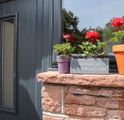 A window ledge with three flower pots and a welcome sign at Lands Brow Lodge in Wigton