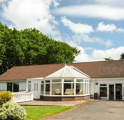A single-story house with a tiled roof a white conservatory and a front garden with bushes at Treetops in Govilon near Abergavenny