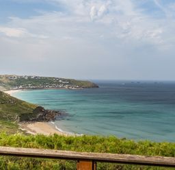A view of a beach and sea with cliffs and houses at Cragford in Sennen Cove
