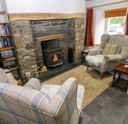 A living room with a fireplace and armchairs at Milk Wood Cottage in Laugharne