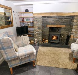 A living room with a fireplace and armchairs at Milk Wood Cottage in Laugharne
