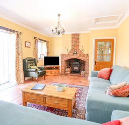A living room with sofas a coffee table a fireplace and a chair at The Meadows Cottage Billingford near Bawdeswell