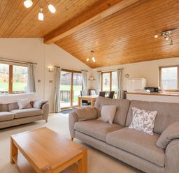 A living area with two sofas a wooden coffee table dining table and chairs and windows at High Tide in Rock