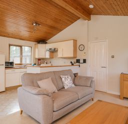 A sofa with cushions in a living room next to a kitchen with white cabinets and a wooden ceiling at High Tide in Rock