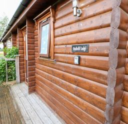 Exterior view of a wooden log cabin with a window a door and a sign that reads Heathcliff Lodge at Heathcliff in Northallerton