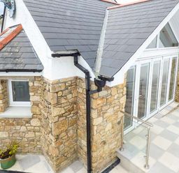 Stone exterior corner of a house with slate roofing and large glass doors on a tiled patio at Chapel Green Studio 2 Polgooth