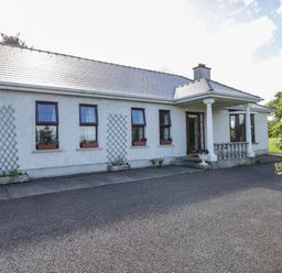 The front exterior of a single-story house with several windows and potted plants near the entrance at Belladrihid Cottage Ballysadare near Sligo County Sligo