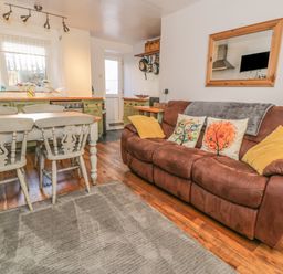 A kitchen and living area with a brown sofa and dining table with chairs at Snowdon View in Llanberis