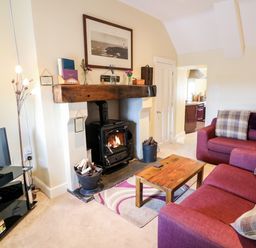 A living room with a fireplace a wooden coffee table a red sofa and a television at Whispering Willows - The Thatch in Carndonagh County Donegal