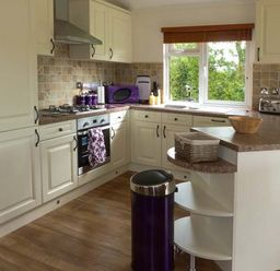 A kitchen with cream cabinets a countertop with appliances and a window at Morgan Lodge in Hewish near Weston-super-Mare