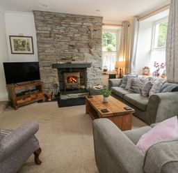 A living room with a stone fireplace and sofas at Teifi House in Cilgerran near Cardigan