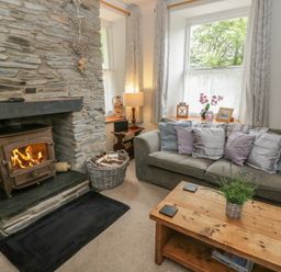 A living room with a fireplace and sofa at Teifi House in Cilgerran near Cardigan