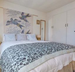 A bedroom with a double bed a decorative blanket bedside tables with lamps a wardrobe and a wall hanging of birds at High House in Newton in Cartmel near Cartmel