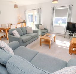 A living room with a sofa, dining table and television at The Haven in Embleton