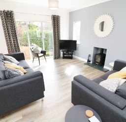 A living room with two grey sofas a chair television and a fireplace at Wysteria Cottage in Windermere