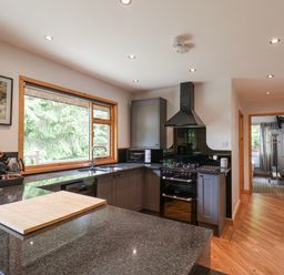 A kitchen with dark countertops cabinets a stove microwave and a window with trees outside at Pond Farm Woodlands in Ugthorpe