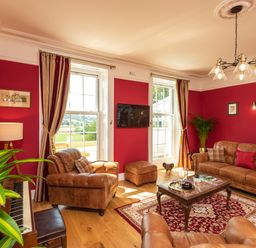 A living room with leather sofas a coffee table and a piano at Old Rectory House Caersws