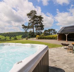 A hot tub with an outdoor table and chairs at The Hayloft Bleddfa near Knighton