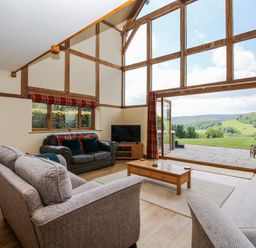 A living room with large windows and furniture at The Hayloft in Bleddfa near Knighton