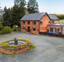 A house with a fountain and flower beds at Ty Newydd in Llangadfan