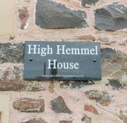 A stone wall with a rectangular sign reading High Hemmel House at High Hemmel House Embleton
