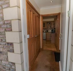 A hallway with wooden doors leading to a kitchen with wooden cabinets at Home Stead Cottage in Embleton