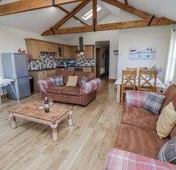 A living room with sofa and kitchen area at Home Stead Cottage in Embleton