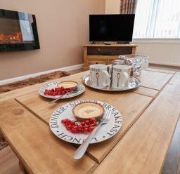 A living room with a coffee table and plates of food at La Rochelle in Whitby