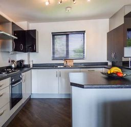 A kitchen with black countertops white cabinets a window with blinds and kitchen appliances at Tehidy in Charlestown