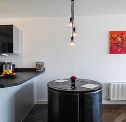 A kitchen with a black countertop and a round black dining table with black chairs at Tehidy in Charlestown