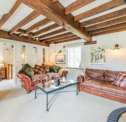 A living room with wooden beams two sofas a glass coffee table and wall art at Grafton Mill in Grafton Flyford near Pershore