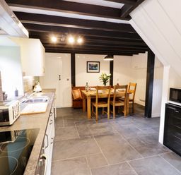 A kitchen with a dining table and chairs and a microwave and toaster at Hen Gelligemlyn - The Annexe in Ganllwyd