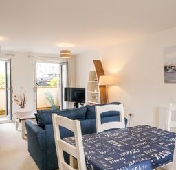 A living room with blue sofas dining table with navy tablecloth and white chairs at Stone's Throw in Charlestown