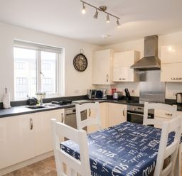 A kitchen with white cabinets a table with a blue tablecloth and four white chairs at Stones Throw in Charlestown