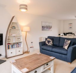 A living room with blue sofas wooden coffee table boat-shaped bookshelf and dining table at Stones Throw in Charlestown