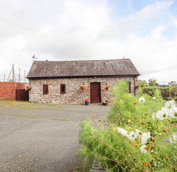 A stone building with a shingled roof and a red door with flowers in pots outside at Bwthyn Ty Newydd in Llangadfan