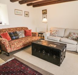 A living room with two sofas a large black trunk coffee table and framed pictures on the wall at The Lookout in Berwick-upon-Tweed