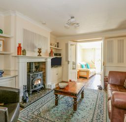 A living room with a wooden coffee table a fireplace and sofas at Camerons Cottage in Swaffham