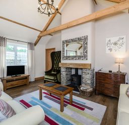 A living room with two sofas wooden coffee table and a stone fireplace at Warbrook in Bradworthy