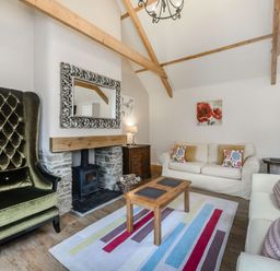 A living room with sofas a green armchair a wooden coffee table and a fireplace at Warbrook in Bradworthy