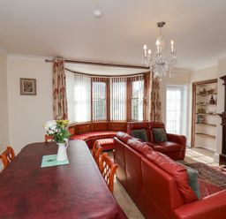 A room with a dining table and chairs a red leather sofa a bay window and a fireplace at Mayfield Manor in Whitby