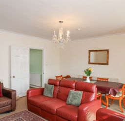 A living room with red and brown leather sofas a dining table with chairs and flowers on it at Mayfield Manor Whitby