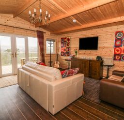 A living room with leather sofas a TV and wall art at The Cabin in Pontardawe