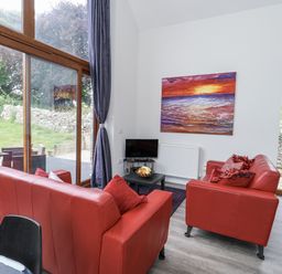 A living room with red sofas and a television at Budmouth in Upwey near Weymouth