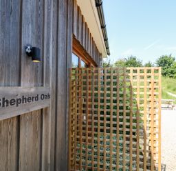 A wooden wall with a sign and trellis at Shepherd Oak in Upwey near Weymouth
