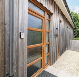 An entrance to a house with a wooden door and stone wall at Everdene Upwey near Weymouth