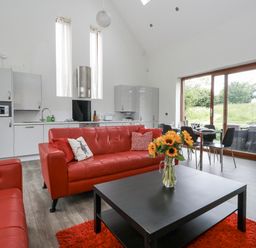 A living room with red sofas and a dining area at Everdene Upwey near Weymouth