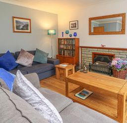 A living room with two sofas with cushions a wooden coffee table fireplace with flowers and a mirror at Trederwen in Rhayader