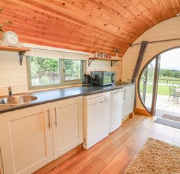 A kitchen with cabinets a sink microwave and dishwasher leading to an outdoor patio at Valley View in Rhayader