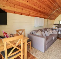 A small wooden interior with a dining table and chairs a gray sofa and a bed at Valley View in Rhayader